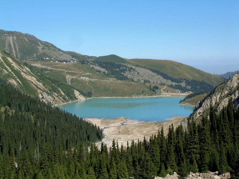 Turquoise Big Almaty Lake surrounded by spruce forest and mountains
