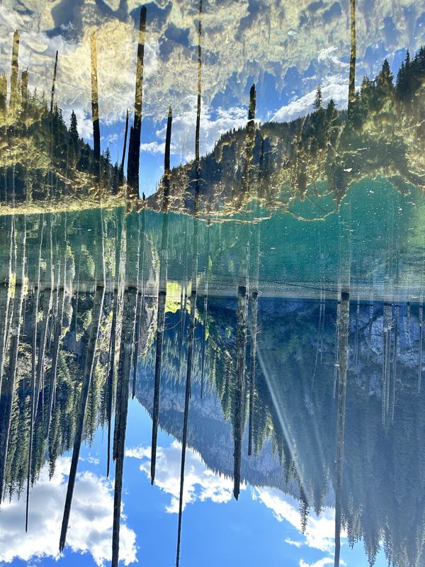 Mirror reflection of the sunken forest in calm Lake Kaindy water